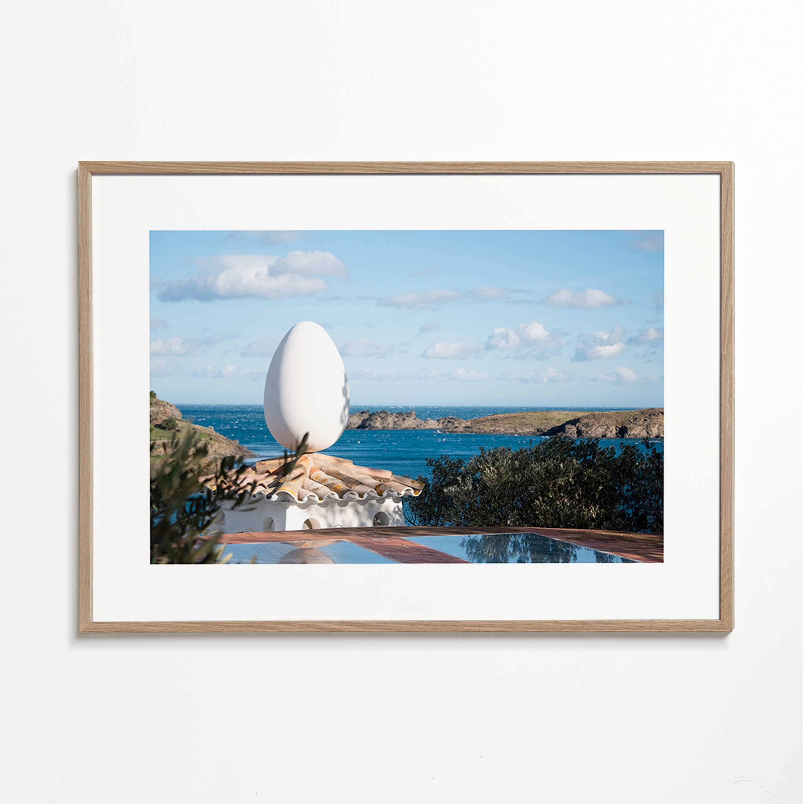 Landscape art featuring an egg sculpture by the sea
